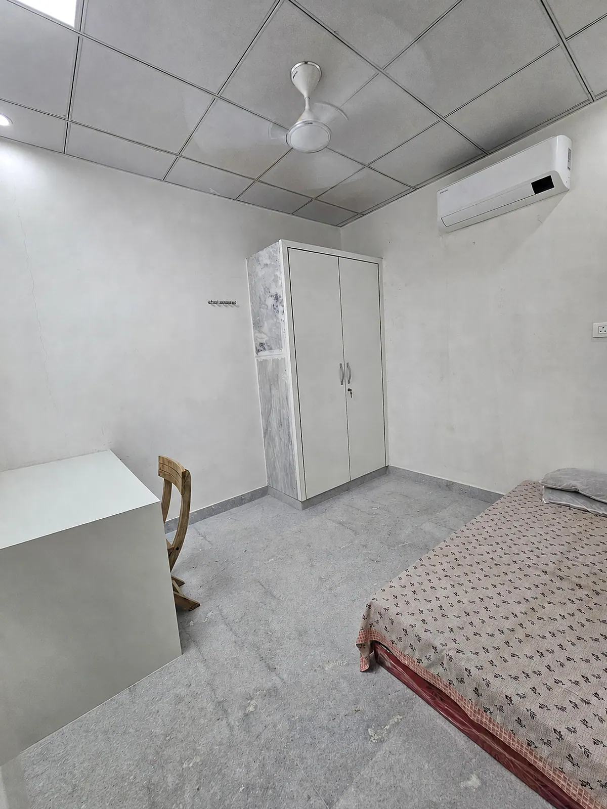 Representative furnished room with a bed, wardrobe, study desk, ceiling fan and split air conditioner
